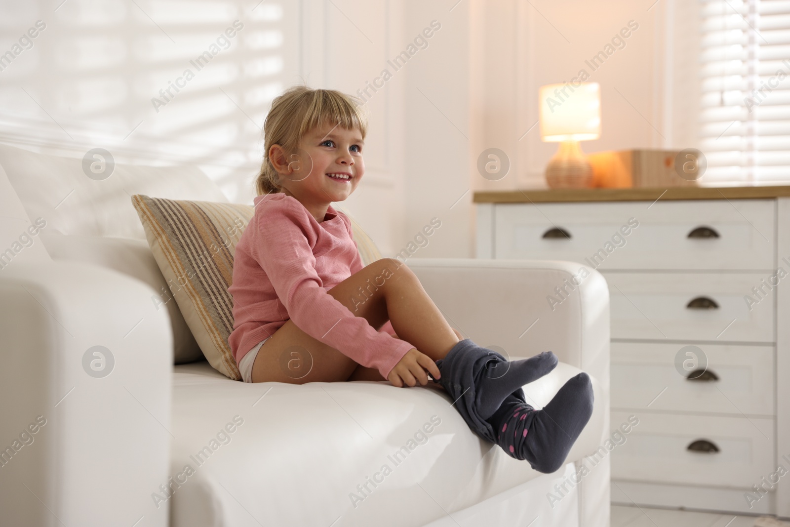 Photo of Little girl putting on soft tights at home. Space for text