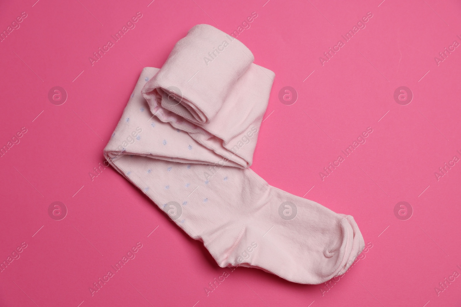 Photo of Beautiful child's tights on pink background, top view