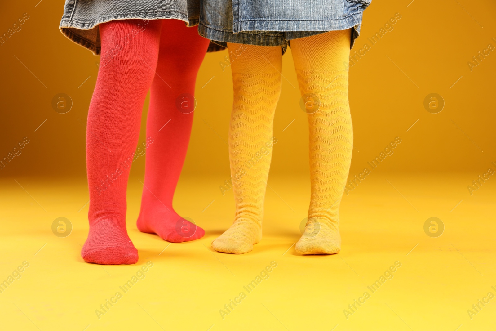 Photo of Kids wearing colorful tights on orange background, closeup