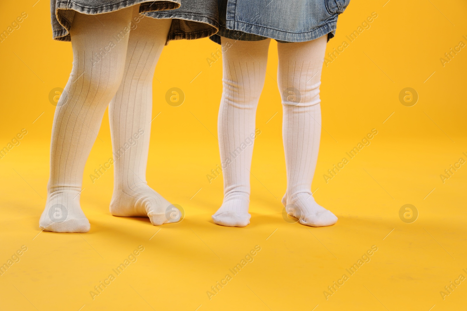 Photo of Kids wearing tights on orange background, closeup