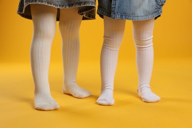 Photo of Kids wearing tights on orange background, closeup