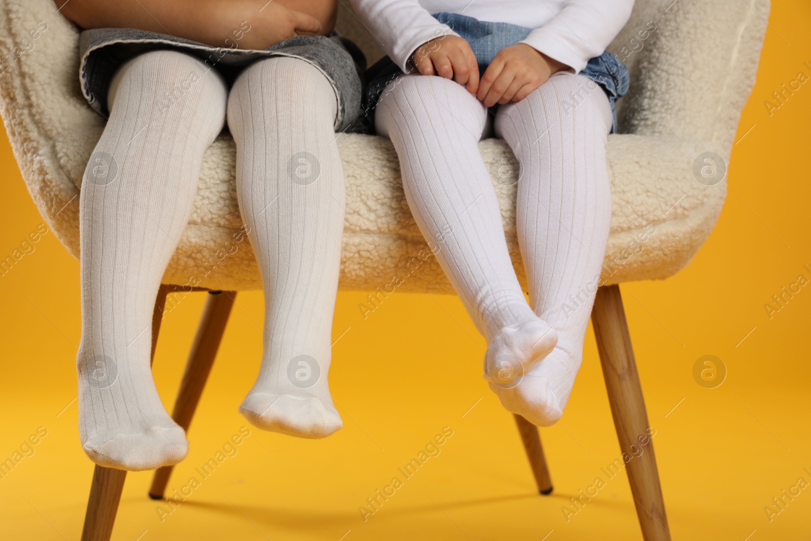 Photo of Kids wearing tights in armchair on orange background, closeup