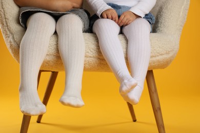 Photo of Kids wearing tights in armchair on orange background, closeup