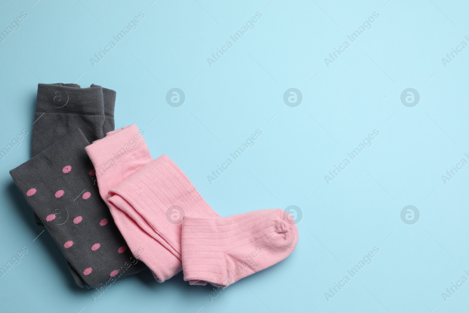 Photo of Different child's tights on light blue background, top view. Space for text