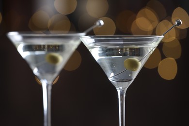 Photo of Martini cocktail with olives in glasses on blurred background, closeup. Bokeh effect