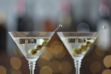 Photo of Martini cocktail with olives in glasses on blurred background, closeup. Bokeh effect