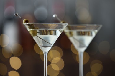 Photo of Martini cocktail with olives in glasses on blurred background, closeup. Bokeh effect