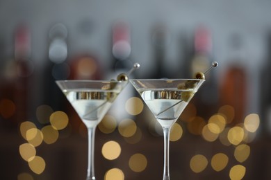 Photo of Martini cocktail with olives in glasses on blurred background, closeup. Bokeh effect