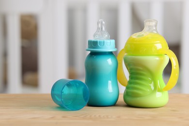 Photo of Feeding bottles with milk on wooden table indoors