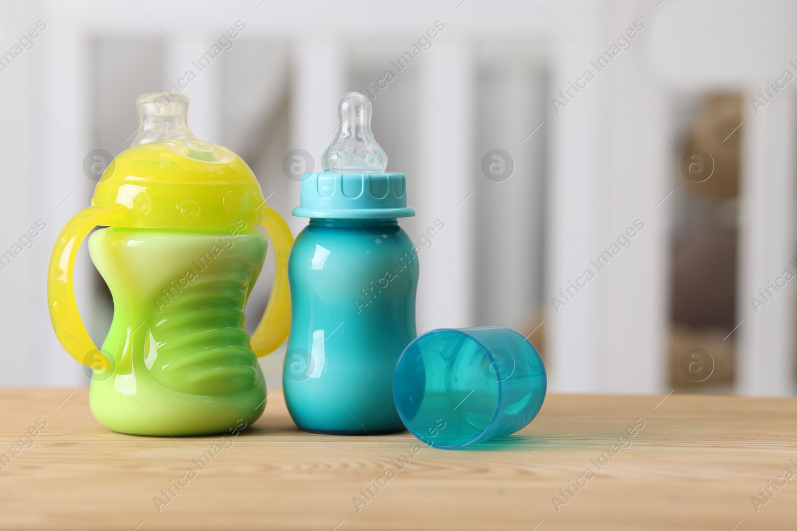 Photo of Feeding bottles with milk on wooden table indoors, space for text