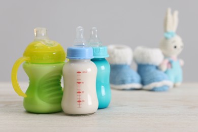 Photo of Feeding bottles with milk on white wooden table, space for text