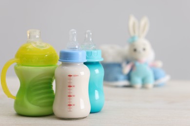 Photo of Feeding bottles with milk on white wooden table, space for text