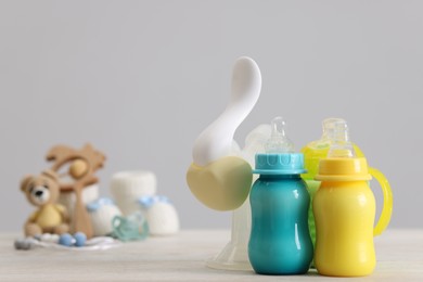 Photo of Feeding bottles with milk and breast pump on white wooden table, space for text