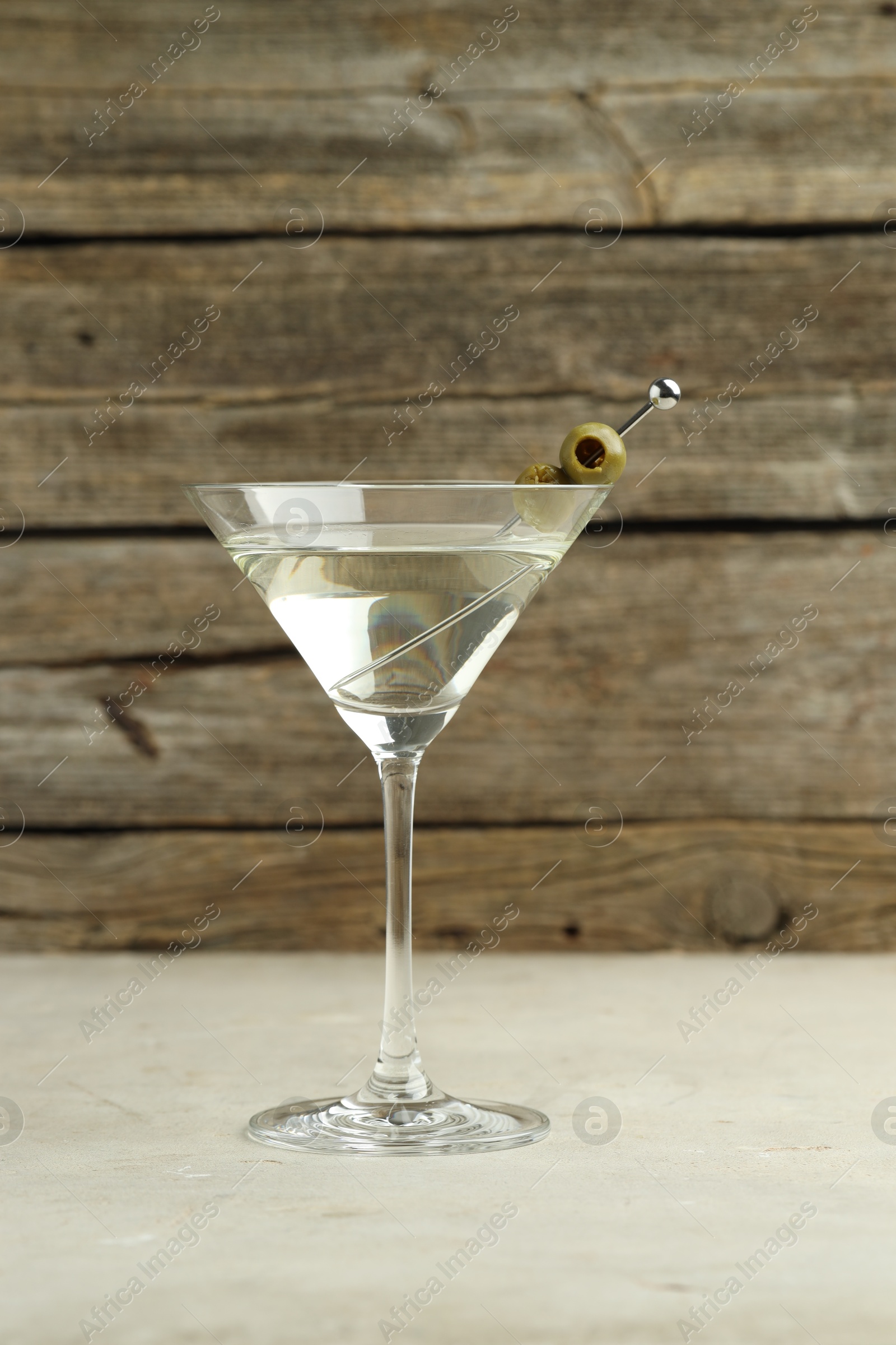 Photo of Martini cocktail with olives in glass on light table