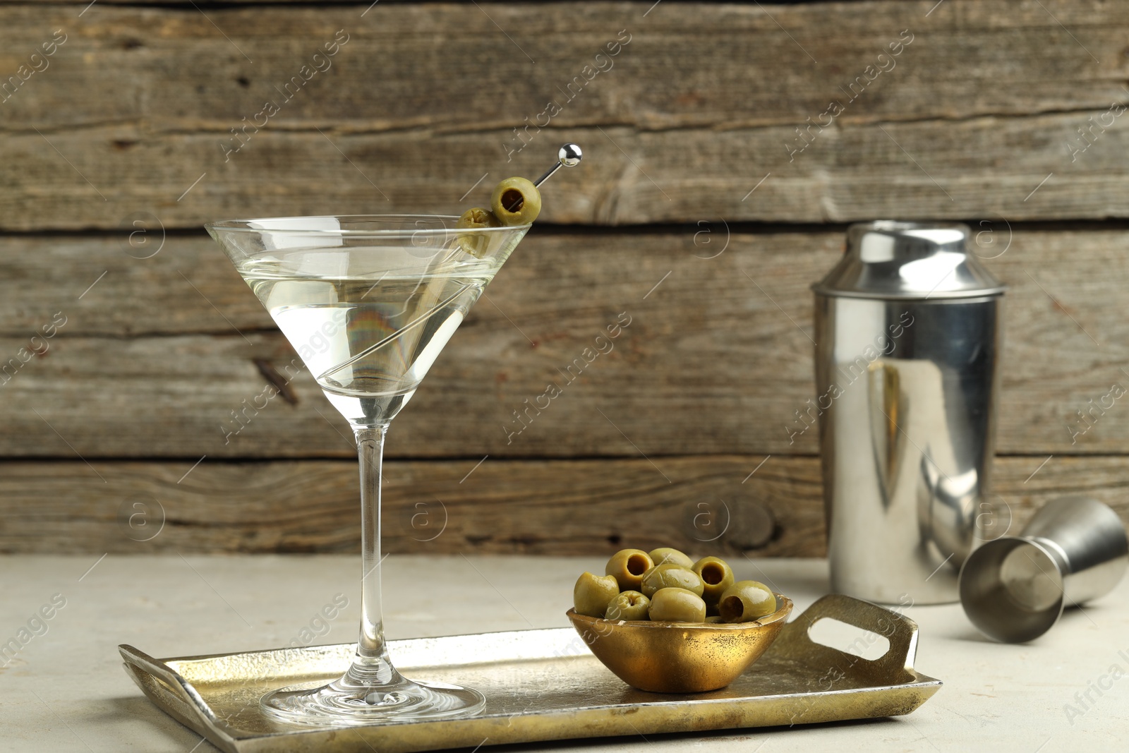 Photo of Martini cocktail with olives in glass and shaker on light table