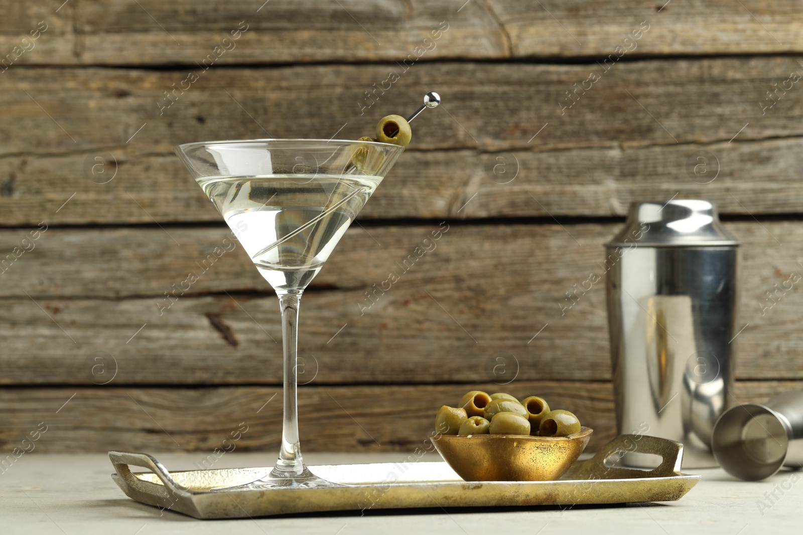 Photo of Martini cocktail with olives in glass and shaker on light table