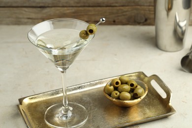 Photo of Martini cocktail with olives in glass and shaker on light table