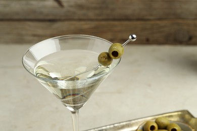 Photo of Martini cocktail with olives in glass on light table, closeup