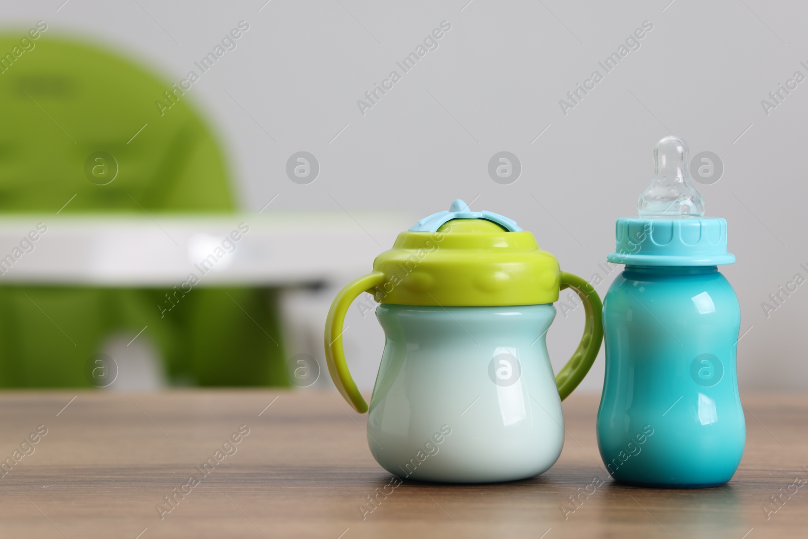 Photo of Feeding bottles with milk on wooden table indoors, space for text