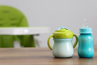 Photo of Feeding bottles with milk on wooden table indoors, space for text