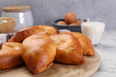 Photo of Delicious pirozhki (stuffed pastry pies) and ingredients on white marble table, closeup