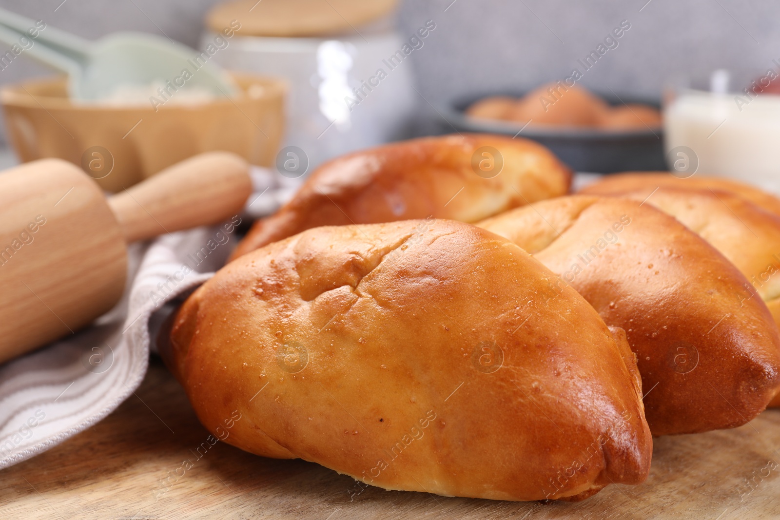 Photo of Delicious pirozhki (stuffed pastry pies) and ingredients on table, closeup