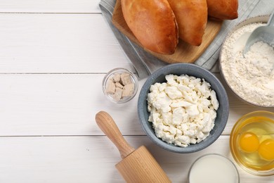 Photo of Delicious pirozhki (stuffed pastry pies) and ingredients on white wooden table, flat lay