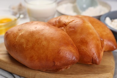 Photo of Delicious pirozhki (stuffed pastry pies) and ingredients on table, closeup