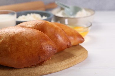 Photo of Delicious pirozhki (stuffed pastry pies) and ingredients on white wooden table, closeup