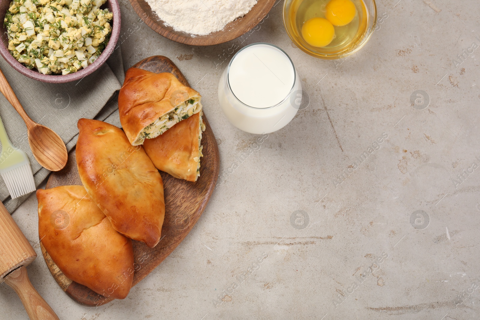 Photo of Delicious pirozhki (stuffed pastry pies) and ingredients on grey table, flat lay. Space for text