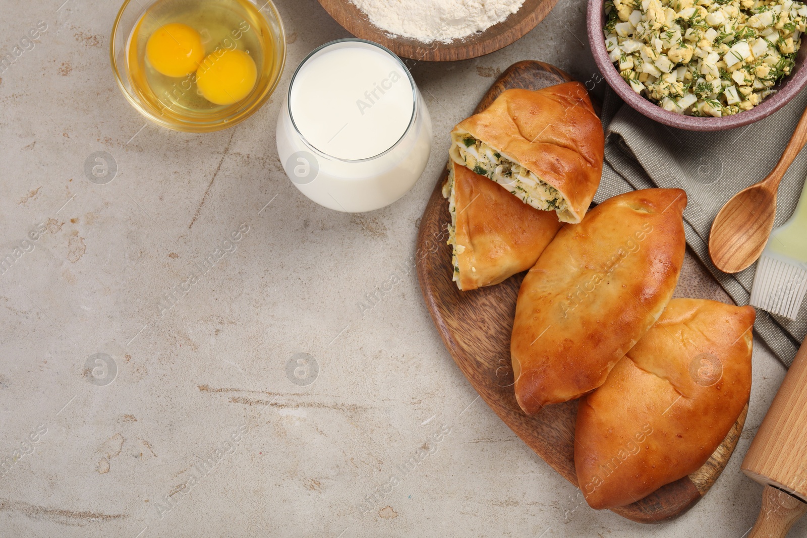 Photo of Delicious pirozhki (stuffed pastry pies) and ingredients on grey table, flat lay. Space for text