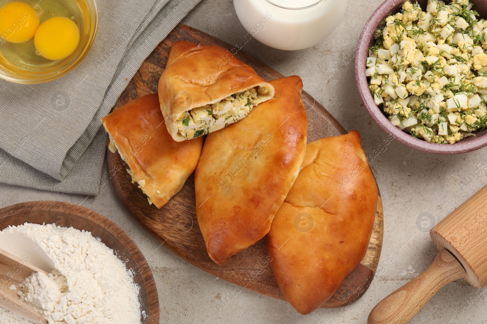 Photo of Delicious pirozhki (stuffed pastry pies) and ingredients on grey table, flat lay