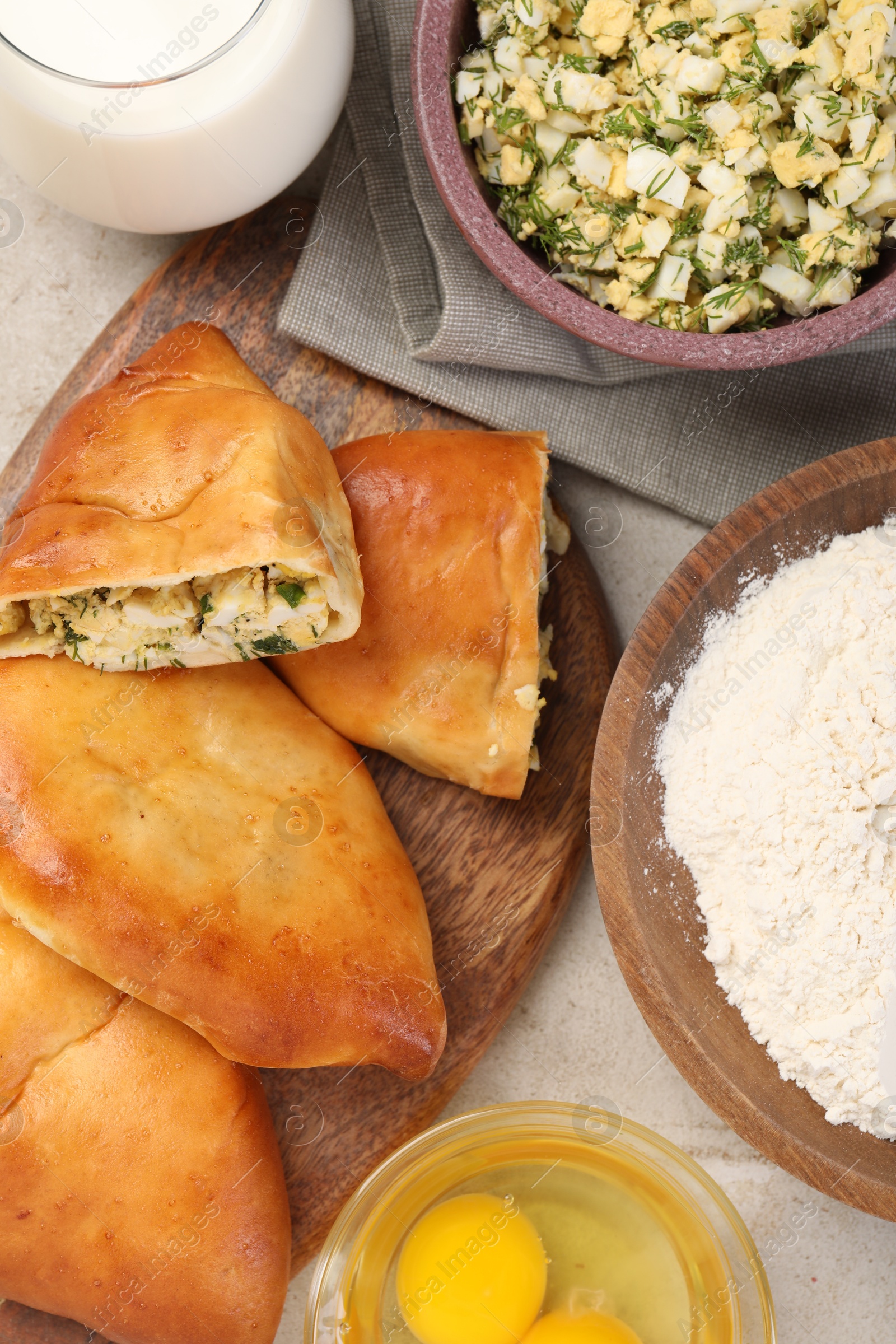 Photo of Delicious pirozhki (stuffed pastry pies) and ingredients on grey table, flat lay