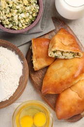 Photo of Delicious pirozhki (stuffed pastry pies) and ingredients on grey table, flat lay