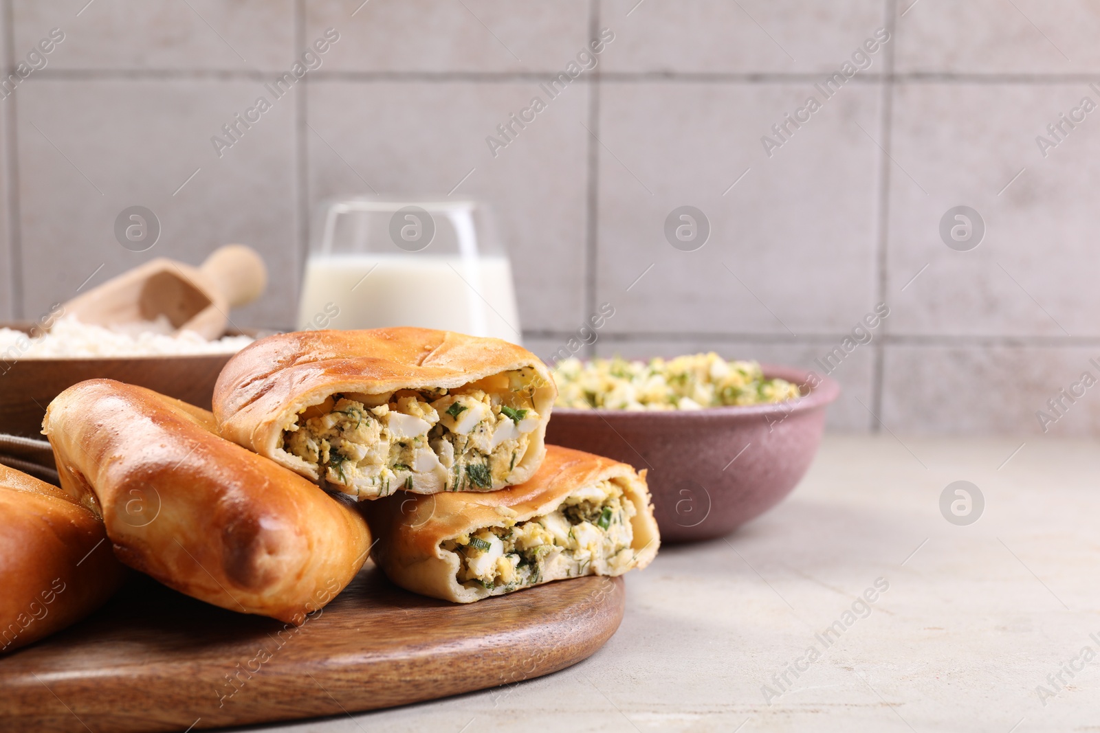 Photo of Delicious pirozhki (stuffed pastry pies) and ingredients on grey table, closeup