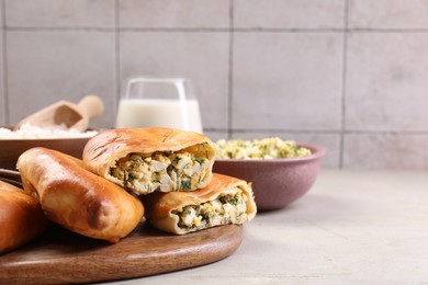 Photo of Delicious pirozhki (stuffed pastry pies) and ingredients on grey table, closeup