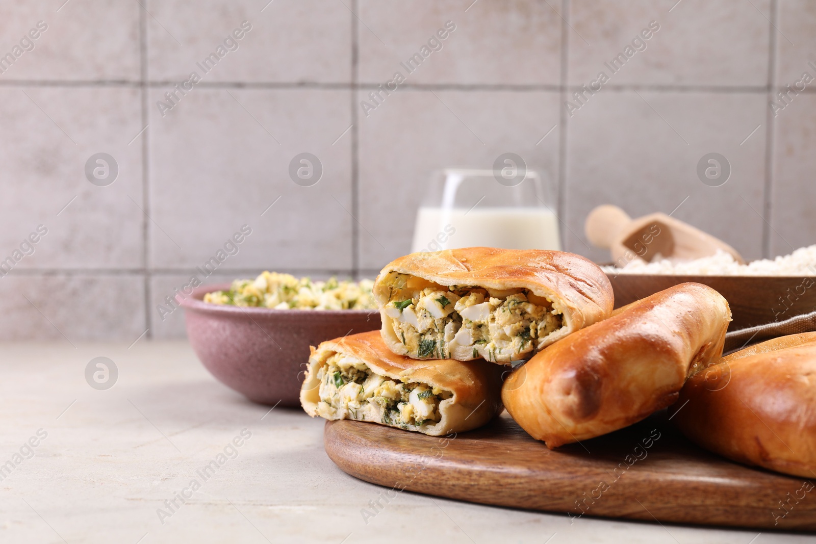 Photo of Delicious pirozhki (stuffed pastry pies) and ingredients on grey table, closeup. Space for text