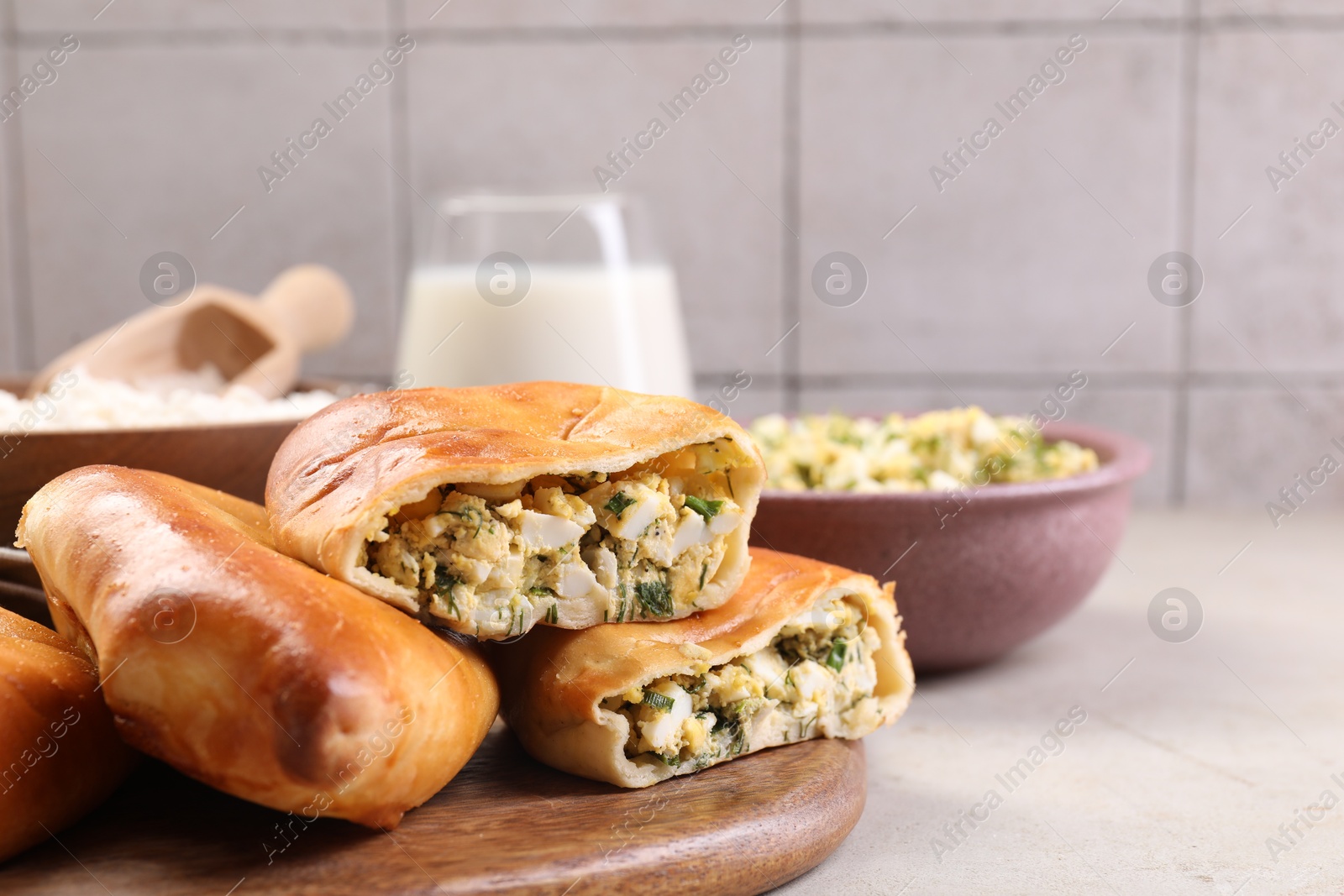 Photo of Delicious pirozhki (stuffed pastry pies) and ingredients on grey table, closeup. Space for text