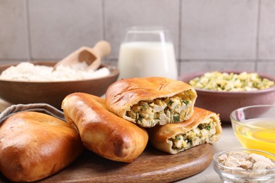 Photo of Delicious pirozhki (stuffed pastry pies) and ingredients on grey table, closeup