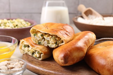 Photo of Delicious pirozhki (stuffed pastry pies) and ingredients on grey table, closeup