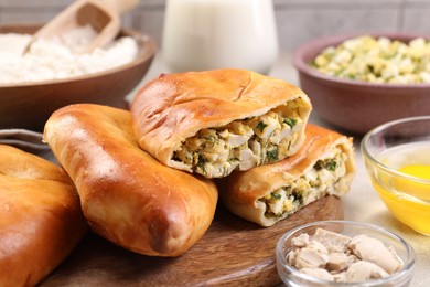 Photo of Delicious pirozhki (stuffed pastry pies) and ingredients on table, closeup