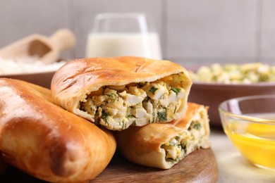 Photo of Delicious pirozhki (stuffed pastry pies) and ingredients on grey table, closeup