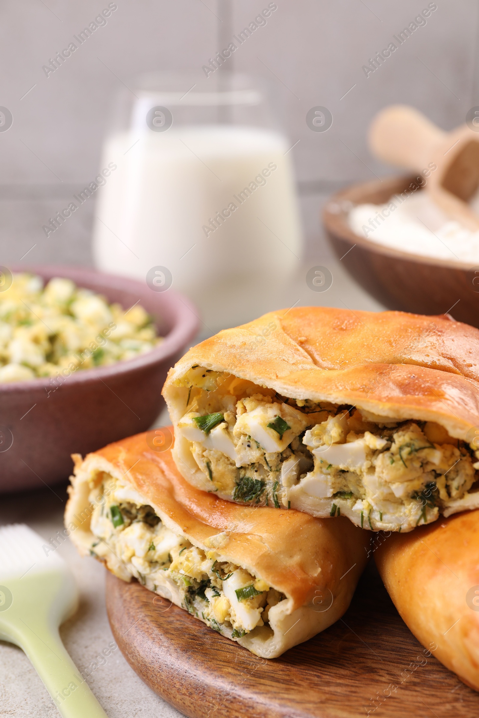 Photo of Delicious pirozhki (stuffed pastry pies) and ingredients on grey table, closeup