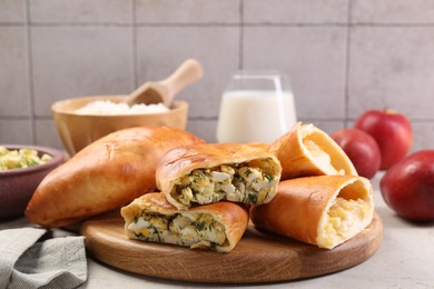 Photo of Delicious pirozhki (stuffed pastry pies) and ingredients on grey table, closeup