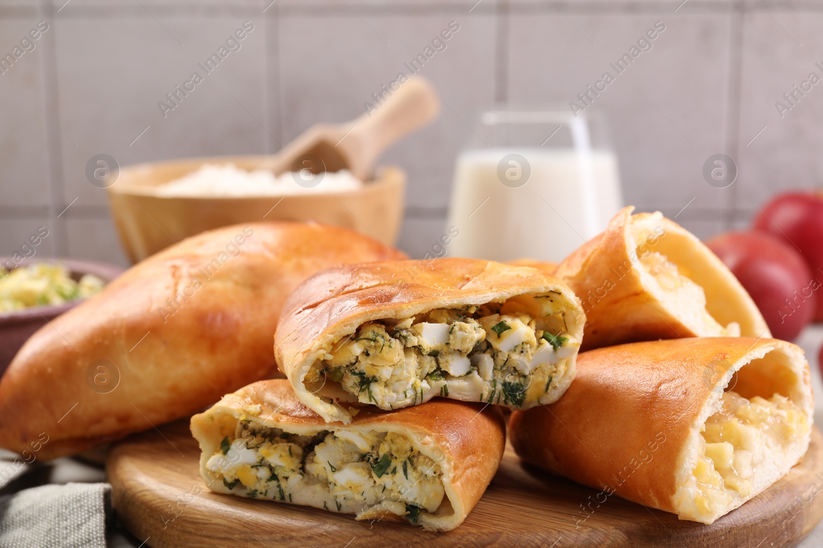 Photo of Delicious pirozhki (stuffed pastry pies) and ingredients on table, closeup