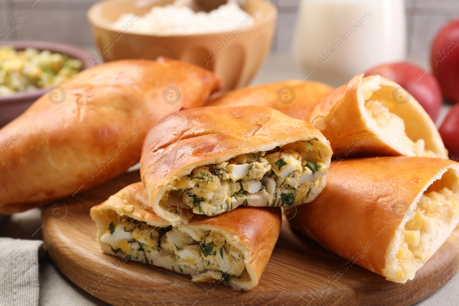 Photo of Delicious pirozhki (stuffed pastry pies) and ingredients on table, closeup