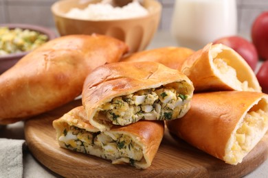 Photo of Delicious pirozhki (stuffed pastry pies) and ingredients on table, closeup