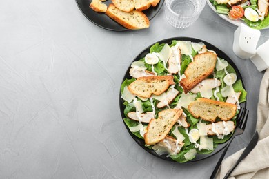 Photo of Delicious Caesar salad with chicken served on grey textured table, flat lay. Space for text