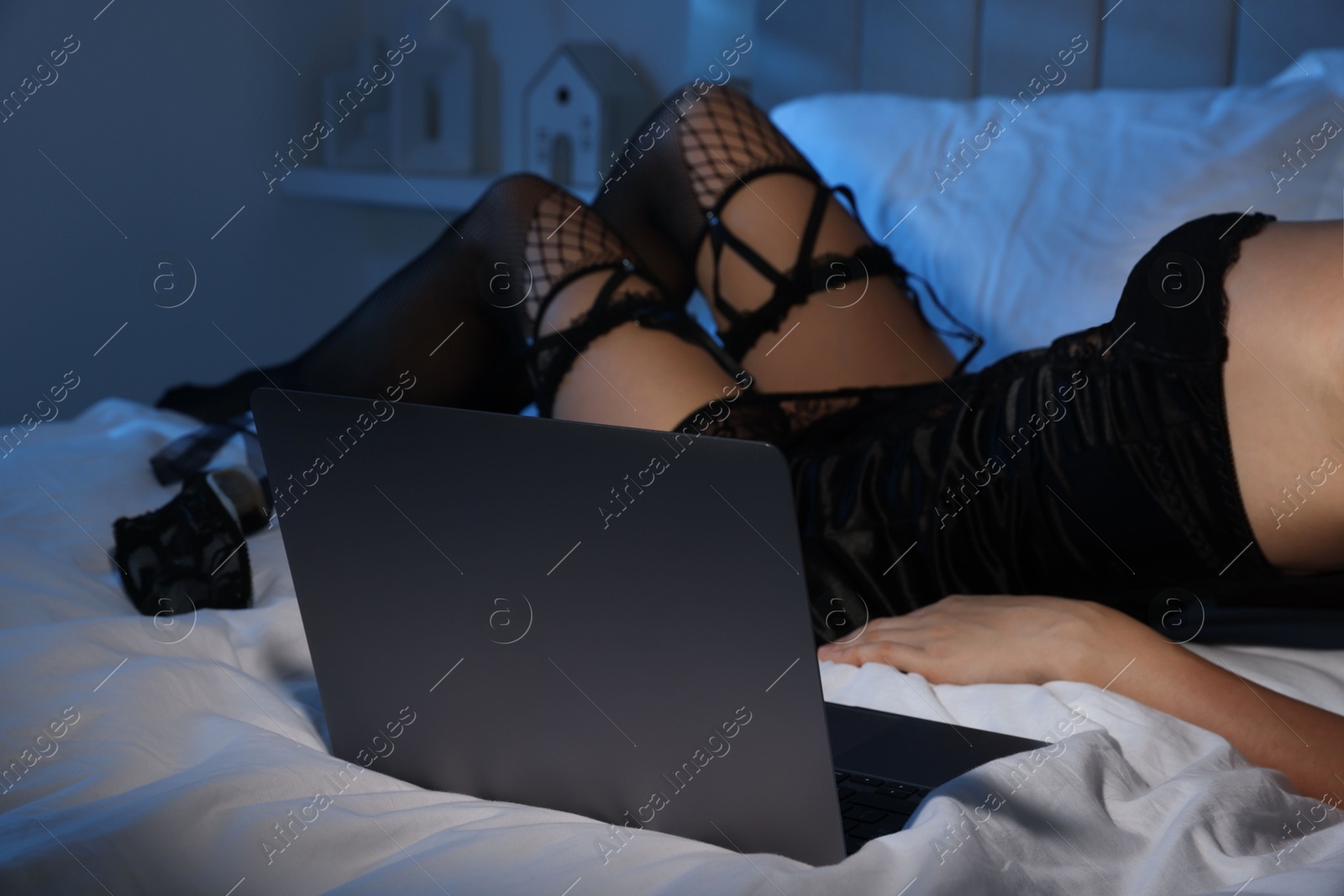 Photo of Prostitution. Webcam model streaming with laptop on bed, closeup