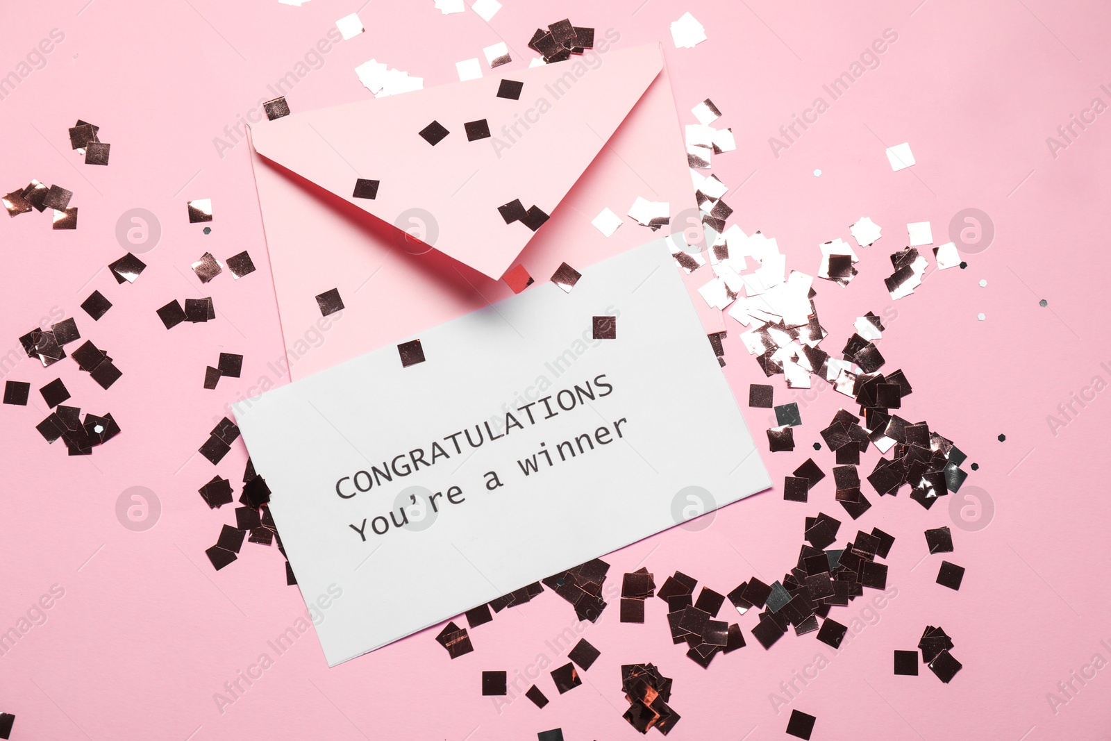 Photo of Card with phrase Congratulations You`re Winner, envelope and confetti on pink background, flat lay